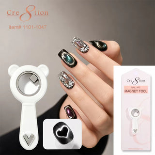 White bear shaped Cre8tion magnet tool beside a hand wearing black and chrome cat eye nails.