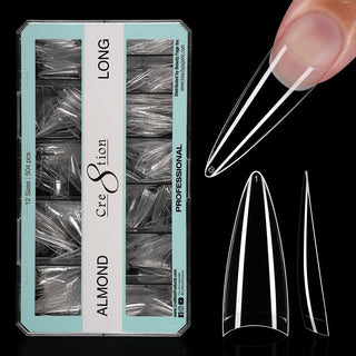 Open mint green box of clear Cre8tion Almond Long tips on black, one tip fitted to a fingertip.