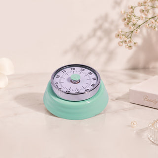 Mint green retro Cre8tion mechanical timer with a numbered dial, on marble with dried flowers.