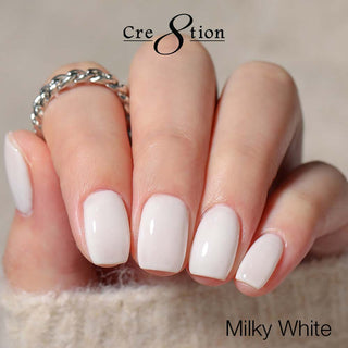 Milky white nail polish on a hand with 'Cre8tion' branding.